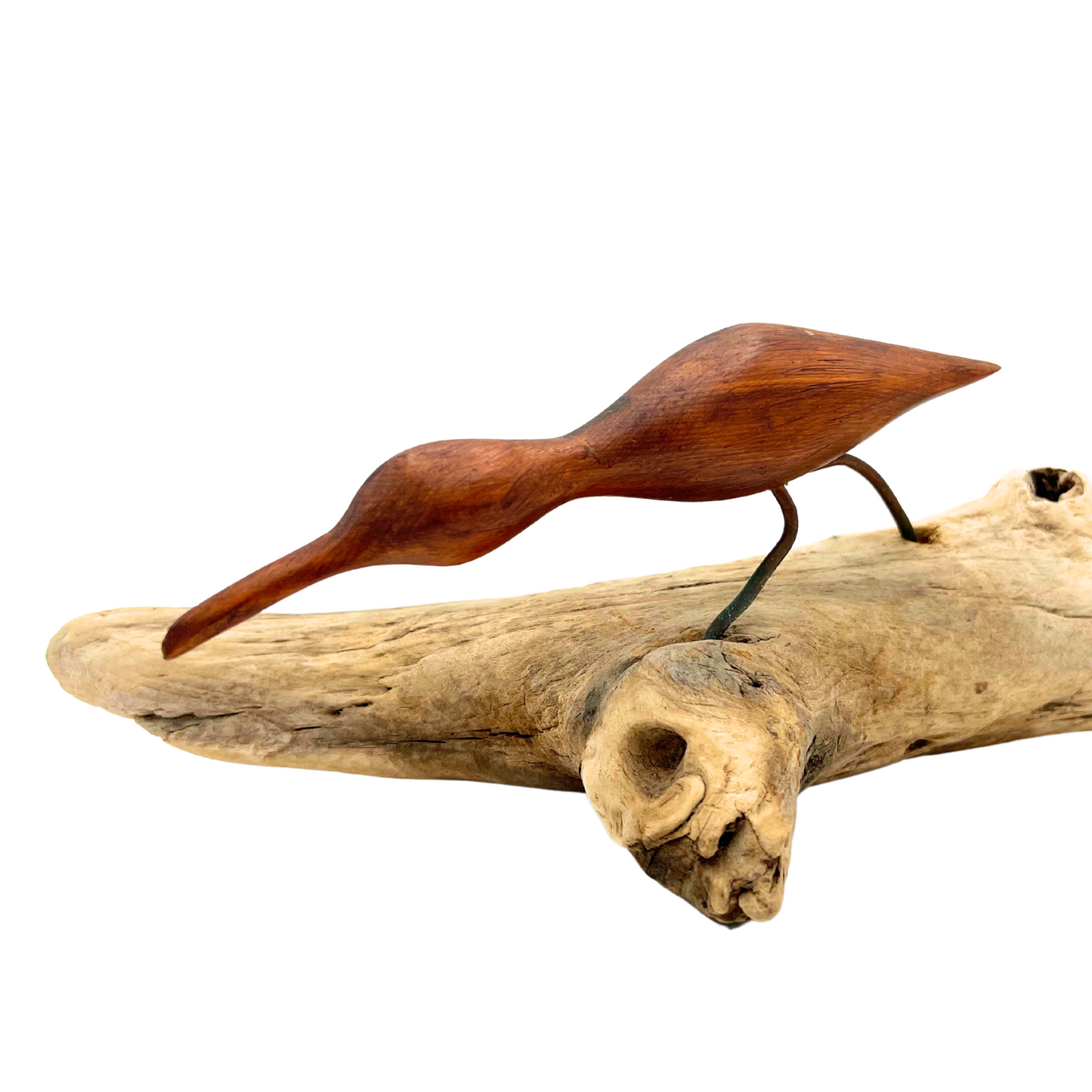 carved wooden shore bird on driftwood